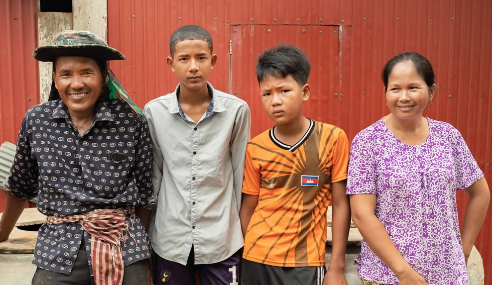 Cheang Sophat, left, and wife Hem Champa, far right, were able to send their second child to college after earning more money from vegetables grown in a nethouse. The couple is confident they will be able to send their third child, 14-year-old Phat Daroth, second from right, to college as well. Photo credit: Max Fannin for UC Davis