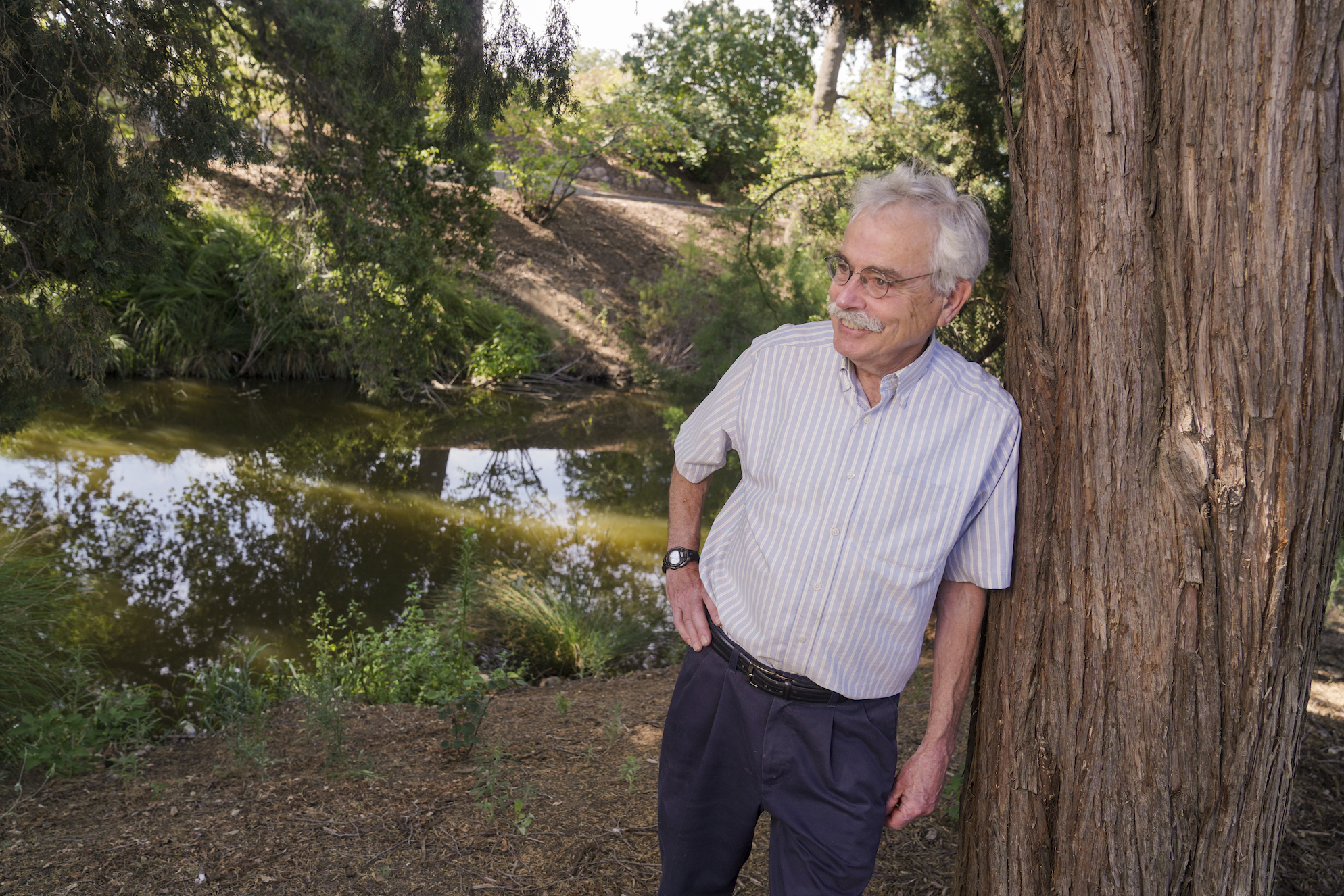 Peter Moyle leans against a redwood tree in the UC Davis Arboretum in June 2022. (Karin Higgins/UC Davis)