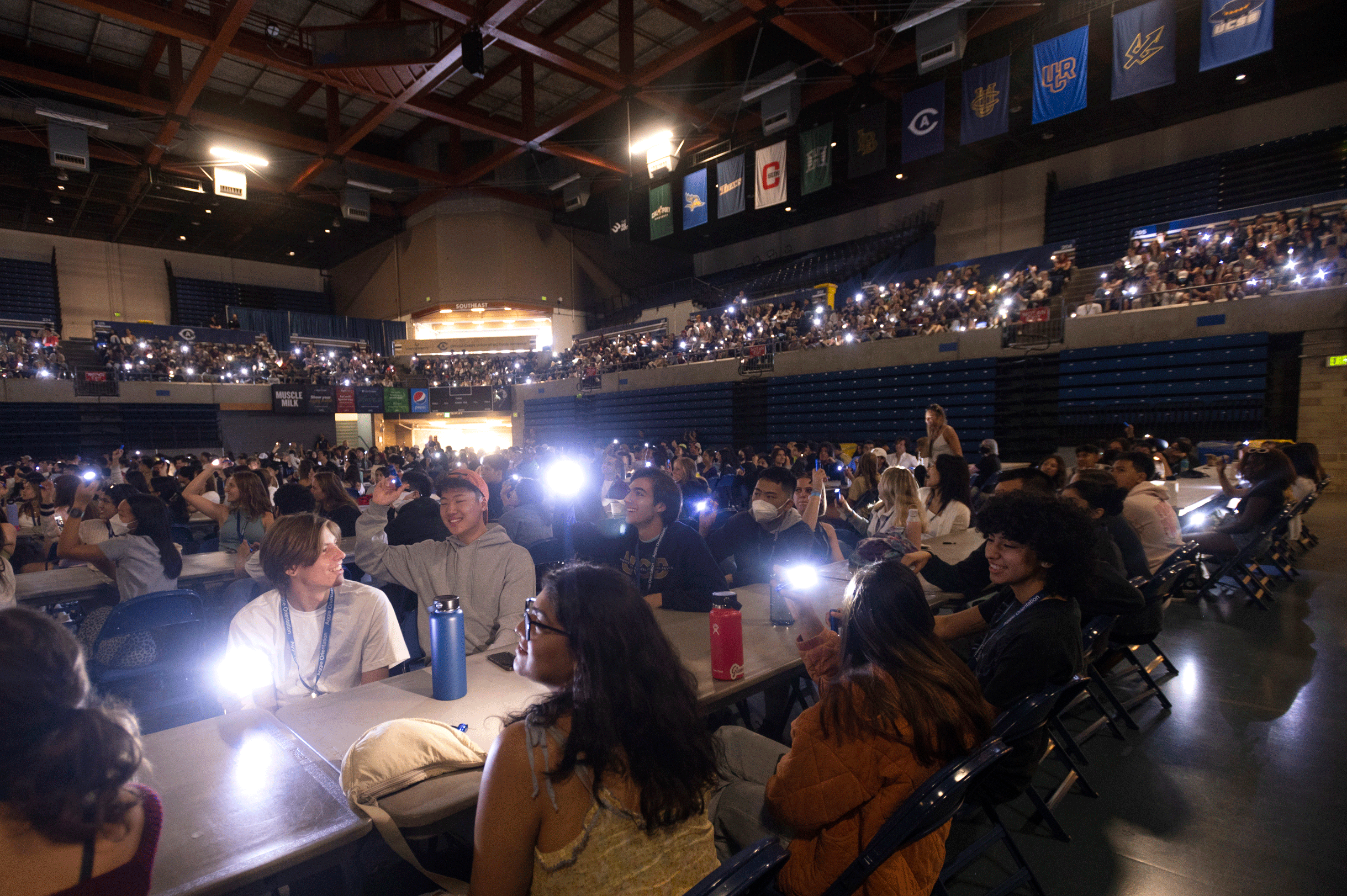 A darkened room filled with students holding up flashlights.