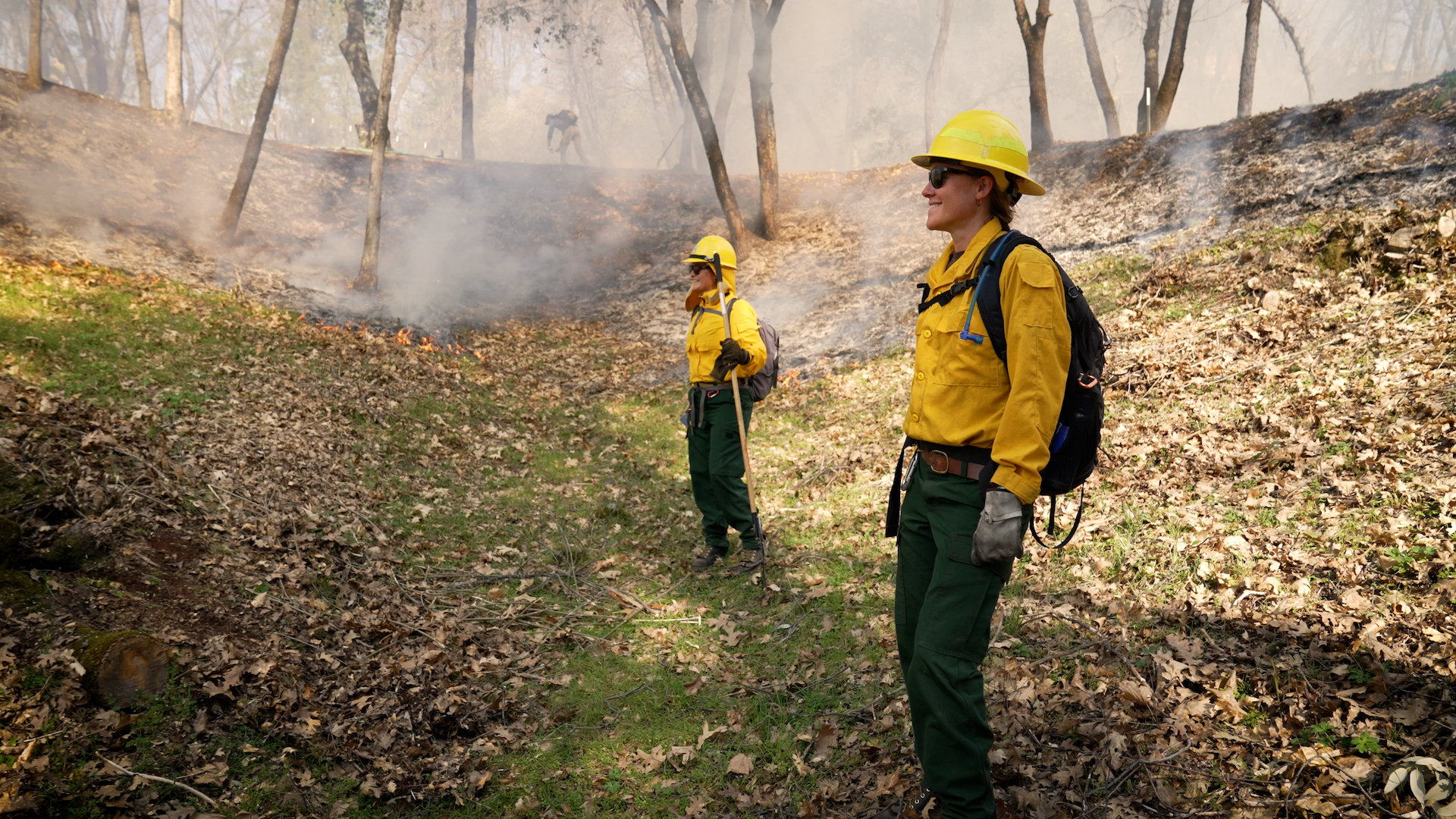 From left, Yoshi Maezumi and Rebecca Wayman of UC Davis stand in Ted Odell's woods during a prescribed burn on the property. (TIm McConville/UC Davis)