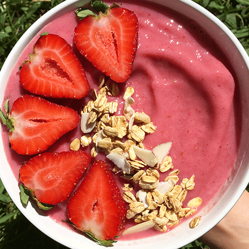 Sliced strawberries with oats over a strawberry smoothie bowl.