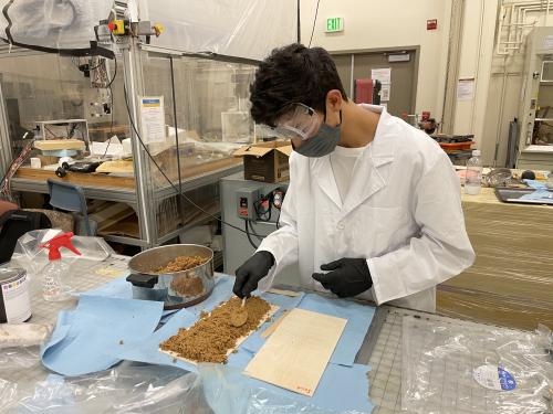 High school student intern Nathan Fanous prepares a sandwich sample with mycelium, biomass and plywood. Photo courtesy of Valeria La Saponara.