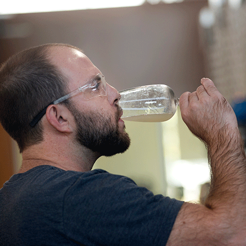 David Makieve, viticulture and enology major, samples white wine after on racking inert gas in white wine for a research project during grape crush.