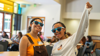 Two students wear sunglasses inside while attending the Aggie JumpStart Kickoff.
