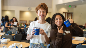 Two students raise a cup at the Aggie JumpStart Kickoff.