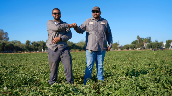 Two agricultural workers fist bump each other in the field at Russell Ranch.