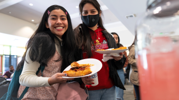 Two students hold slices of pizza at the Slice of Advising event.