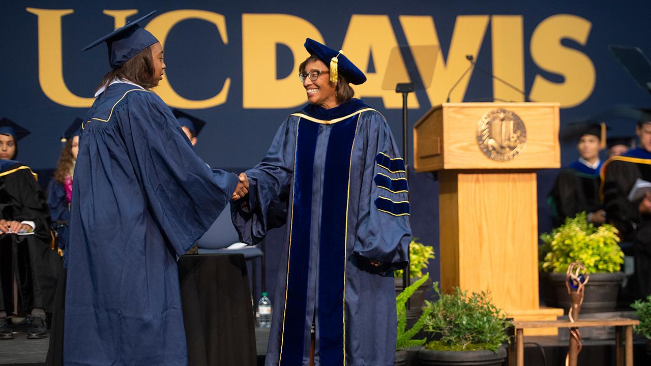 Helene Dillard shaking a newly graduated student's hand at the UC Davis CA&ES commencement.