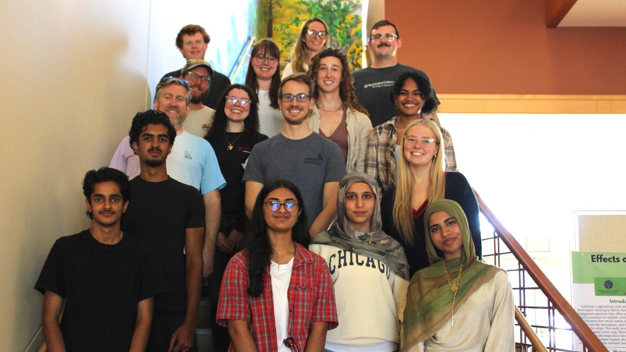 Group photo of young students and college mentors smiling on indoor staircase