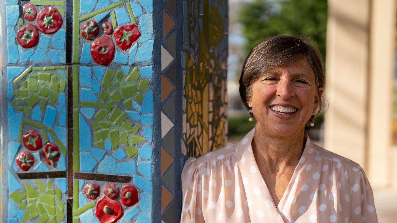 Wolf Prize recipient Pam Ronald outside Robbins Hall, leaning against pillar decorated with a ceramic mosaic mural. (Joel Mackendorf/UC Davis)