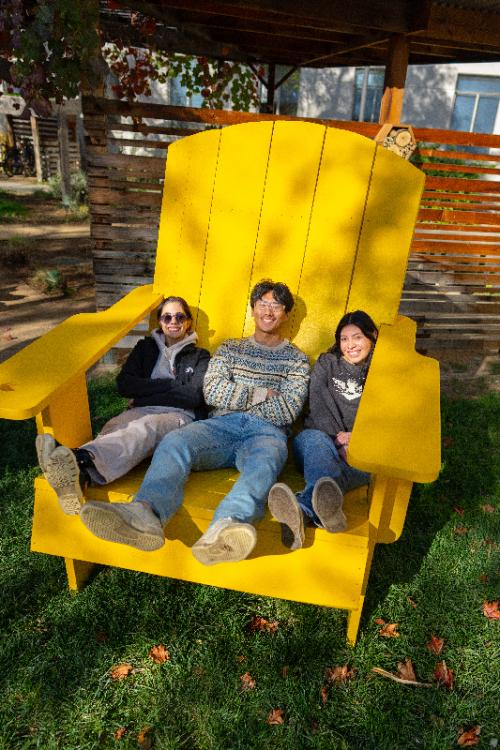 three students in a big yellow chair