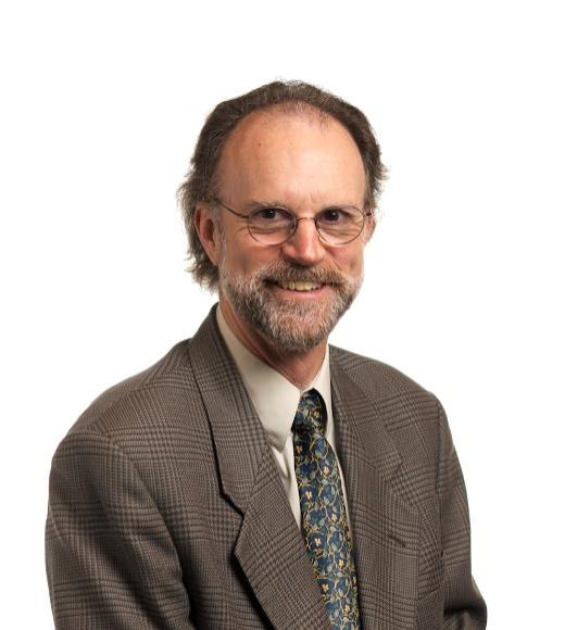 Formal headshot of smiling bearded man in glasses and suit on white background