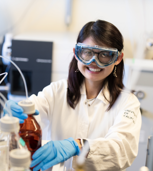 A researcher, wearing goggles and gloves, working in a lab.