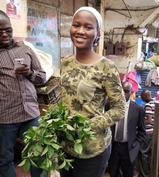 Deedi Soghossou, a graduate of the African Plant Breeding Academy, samples a spider plant, a popular, but neglected leafy vegetable eaten across Africa. (African Orphan Crops Consortium)