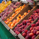 A row of stone fruit in wooden boxes at a Farmers market.