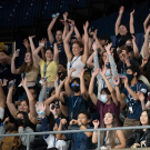 Students stand and wave their hands in the air while participating in the wave at the UC UC Center during College Welcome.
