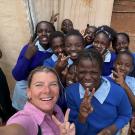 A woman takes a selfie with a group of children.