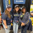 Two students pose with Dean Helene Dillard at the UC Davis booth in Tulare, CA during World Ag Expo.