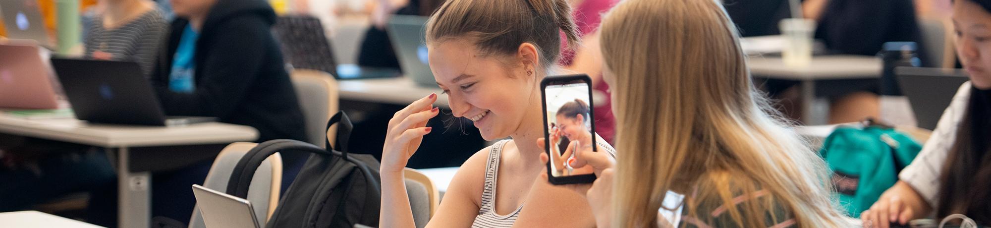 Ellery Quinn, a food science major, bows her head with a smile as her diet work is used as a good example and her friend using a cell phone to record her shyness during Nutrition 10 in California Hall on May 7, 2019. 